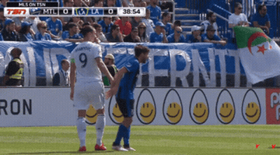 Woman In Blue Dress Touching Belly In Crowd GIF