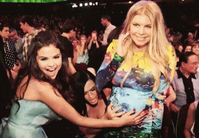 Woman In Blue Dress Touching Belly In Crowd GIF