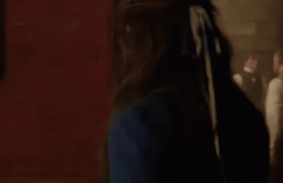 Woman In Blue Dress With Man In Suit Behind Her GIF