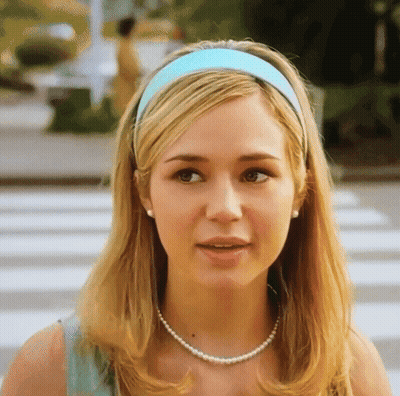 Woman In Blue Headband And Pearls Looking At Camera GIF