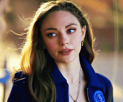 Woman In Blue Jacket And Earrings Looking At Camera GIF