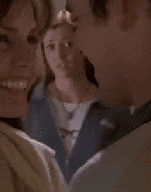 Woman In Blue Jacket And Glasses Standing In Front Of Bookshelf GIF
