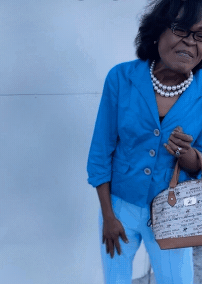 Woman In Blue Jacket And Pearls Holding Beverly Hills Bag GIF