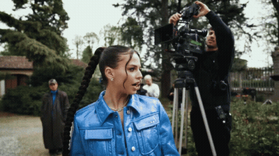 Woman In Blue Jacket In Front Of Cameraman GIF