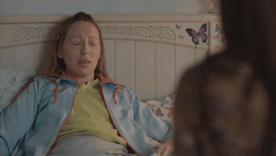 Woman In Blue Jacket Laying On Bed With Butterflies GIF