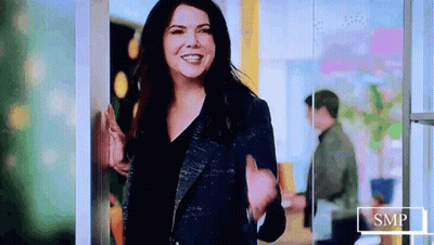 Woman In Blue Jacket Smiling And Waving GIF