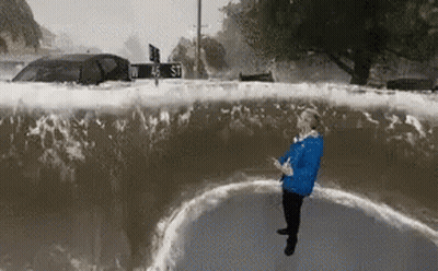Woman In Blue Jacket Standing In Flooded Street GIF