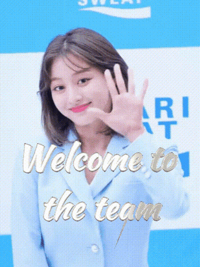 Woman In Blue Jacket Waving At Welcome To The Team Sign GIF