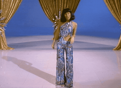 Woman In Blue Jumpsuit Dancing Beside Sesame Street Character GIF