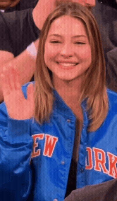 Woman In Blue New York Jacket Smiling And Waving GIF