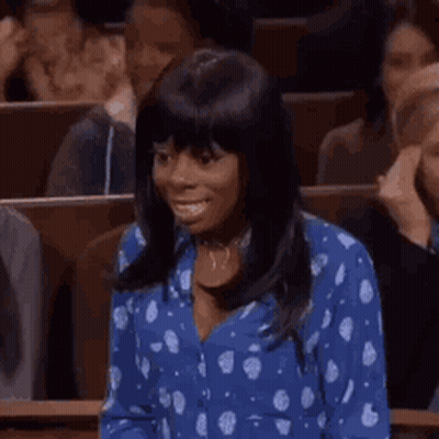 Woman In Blue Polka Dot Shirt Smiling In Crowd GIF