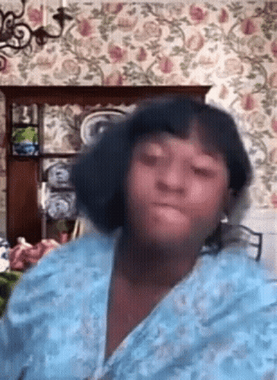 Woman In Blue Robe Sitting With Floral Wallpaper GIF