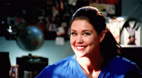 Woman In Blue Scrub Top Smiling In Front Of Globe GIF