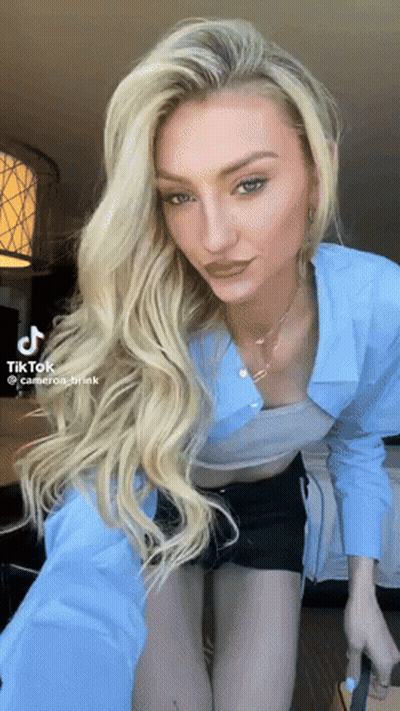 Woman In Blue Shirt And Black Shorts Taking Selfie With TikTok Watermark GIF
