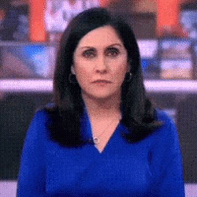 Woman In Blue Shirt And Earrings Looking At Camera GIF