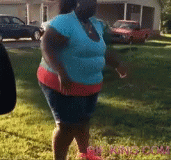 Woman In Blue Shirt And Red Shorts Standing In Grass GIF