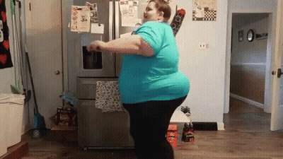 Woman In Blue Shirt Dancing In Front Of Refrigerator GIF