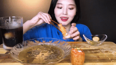 Woman In Blue Shirt Eating Fried Food With Chopsticks GIF