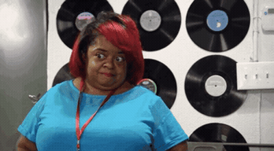 Woman In Blue Shirt In Front Of Record Wall GIF