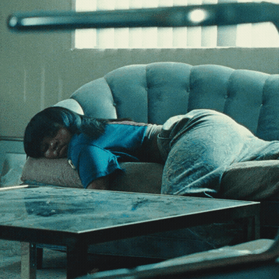 Woman In Blue Shirt Laying On Grey Couch GIF