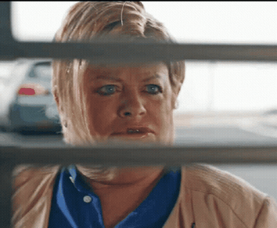 Woman In Blue Shirt Looking Through Fence GIF