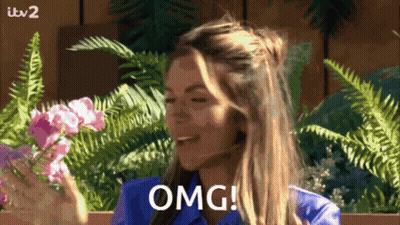 Woman In Blue Shirt Saying OMG With Flowers And Ferns GIF