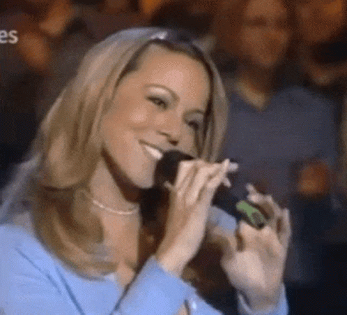 Woman In Blue Shirt Singing Into Microphone In Front Of Crowd GIF