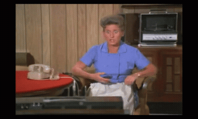 Woman In Blue Shirt Sitting By Record Player And Telephone GIF