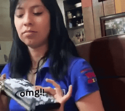 Woman In Blue Shirt Sitting In Booth Holding Cell Phone GIF