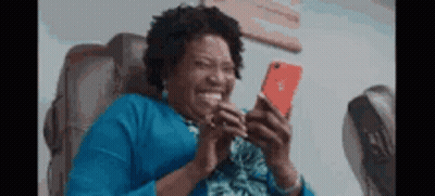 Woman In Blue Shirt Sitting Looking At Phone GIF