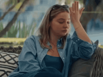 Woman In Blue Shirt Sitting On Couch Hand On Forehead GIF