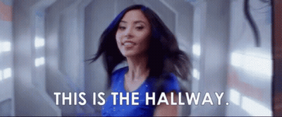 Woman In Blue Shirt Smiling In Hallway GIF