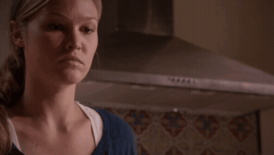 Woman In Blue Shirt Standing In Front Of Stove Hood GIF