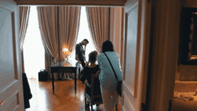 Woman In Blue Shirt Standing Next To Woman In Chair GIF