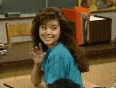 Woman In Blue Shirt Waving At Desk GIF