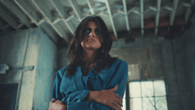 Woman In Blue Shirt With Exit Sign GIF