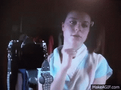 Woman In Blue Shirt With Hands Up In Dark Room GIF