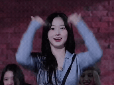 Woman In Blue Sweater Dancing In Front Of Brick Wall GIF