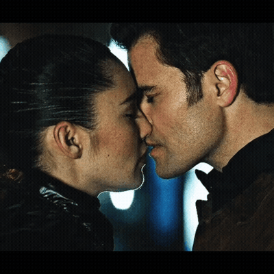 Woman In Blue Sweater Kissing Man In Brown Jacket GIF