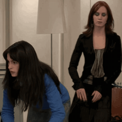 Woman In Blue Sweater Kneeling Next To Woman In Black Jacket GIF
