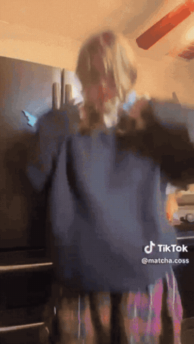 Woman In Blue Sweater Plaid Skirt Dancing By Refrigerator GIF
