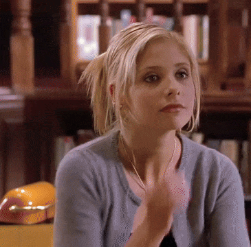 Woman In Blue Sweater Sitting In Front Of Bookcase GIF