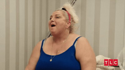 Woman In Blue Tank Top Smiling In Front Of TLC Wall GIF
