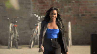 Woman In Blue Top And Black Pants Walking Down Sidewalk GIF