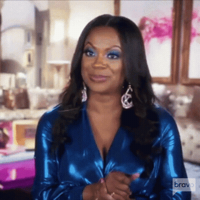 Woman In Blue Top And Earrings Sitting GIF