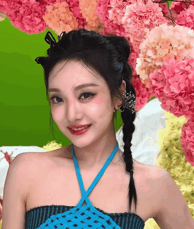 Woman In Blue Top In Front Of Pink And Yellow Flowers GIF