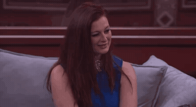Woman In Blue Top Sitting On Couch With Hands On Chin GIF
