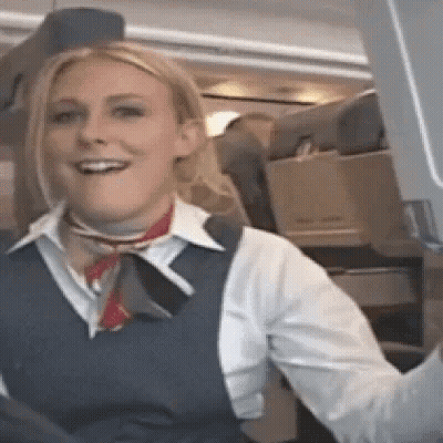 Woman In Blue Vest Smiling On Airplane GIF