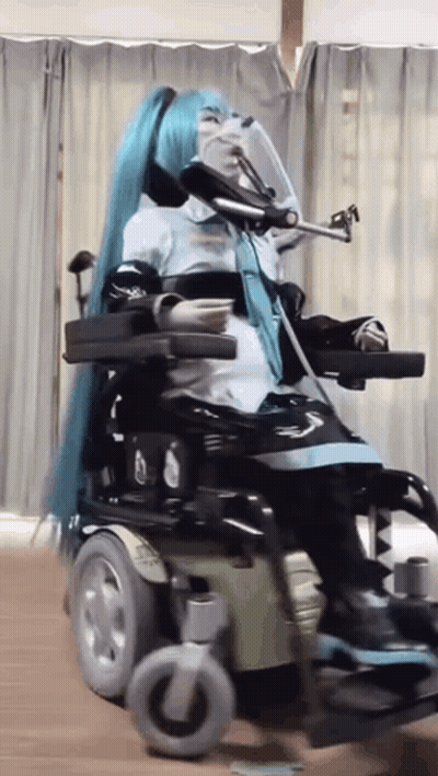 Woman In Blue Wig Sitting In Wheelchair GIF