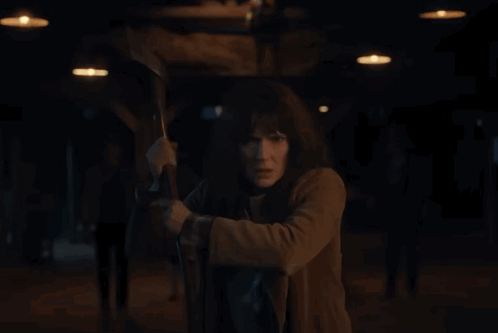 Woman In Brown Coat Holding Axe GIF